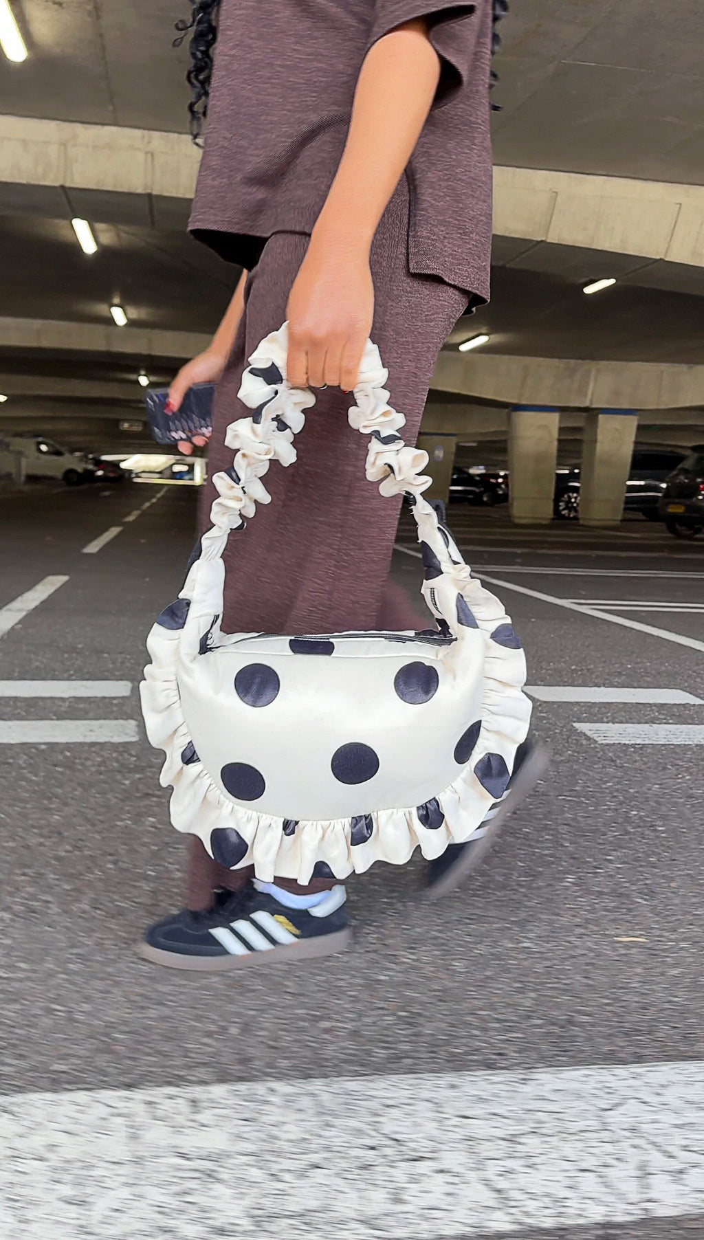 Person holding a polka dot handbag in an underground parking lot