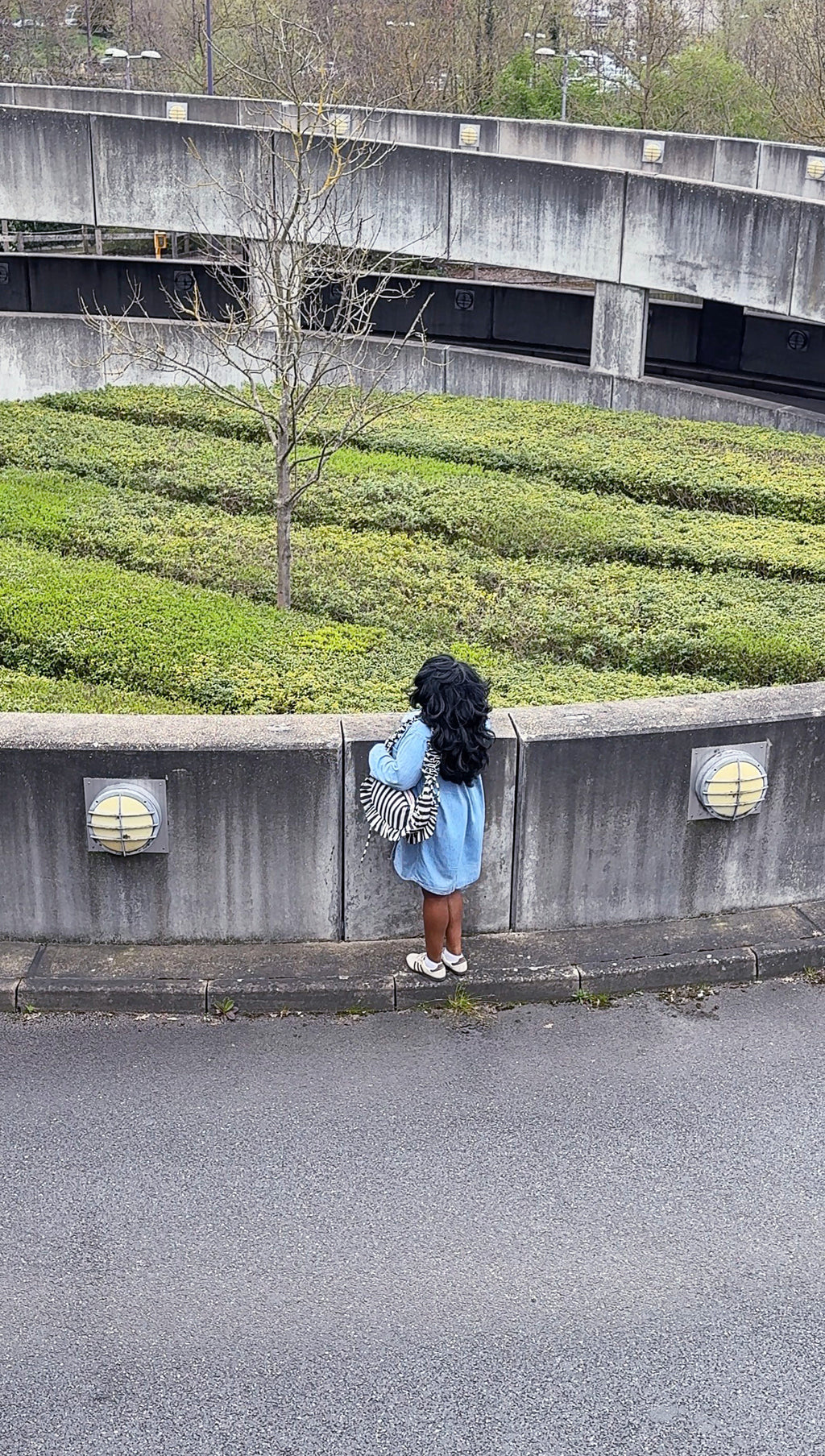 navy and white striped ruffled crescent bag styled with a denim shirt, pictured in a weathered parking lot exit.