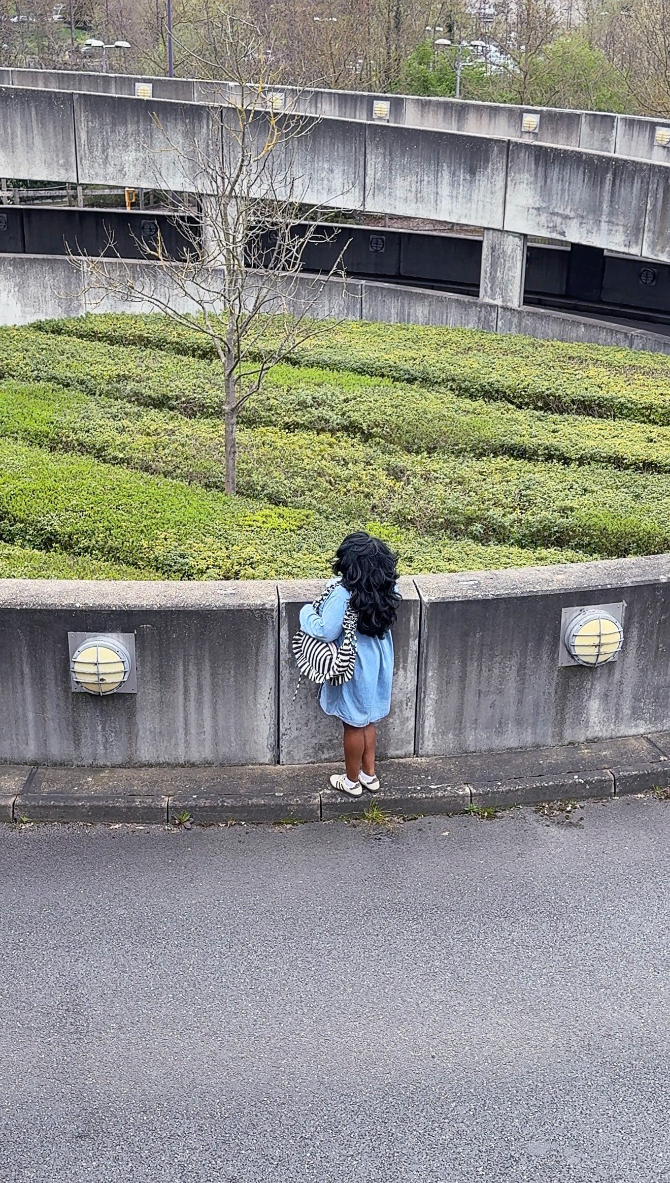 navy and white striped ruffled crescent bag styled with a denim shirt, pictured in a weathered parking lot exit.