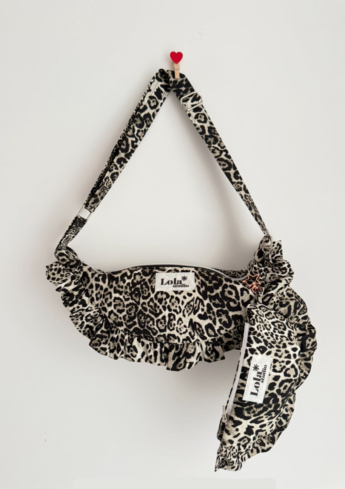 Leopard print bag with ruffles and a visible brand label on a light gray background